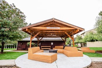 a pavilion with wooden benches and a fire pit